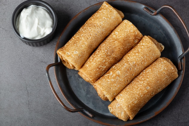 Panqueques finos o crepes rellenos de requesón sobre fondo gris