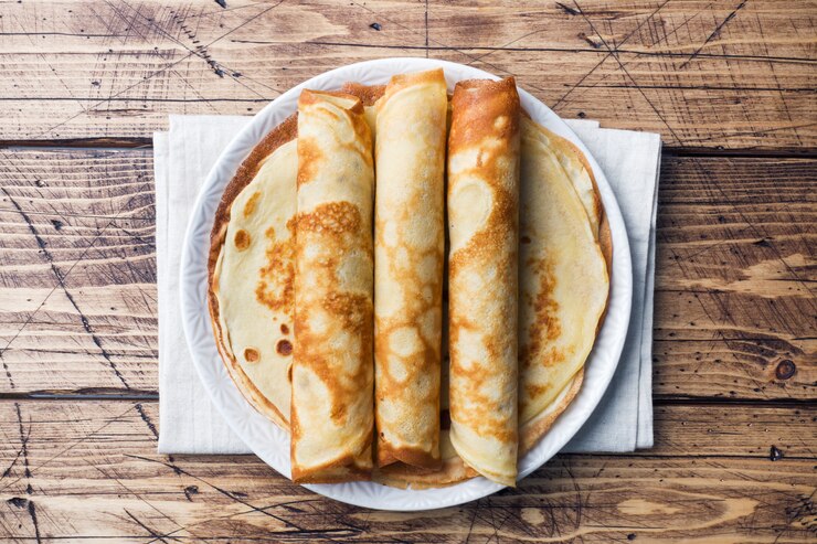 Panqueques finos en un plato. Fondo de madera De cerca.