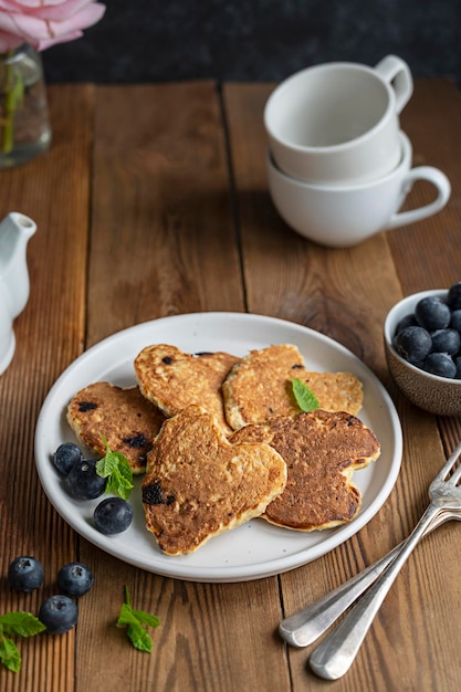 Panqueques en forma de corazón con arándanos frescos Desayuno matutino deliciosos panqueques veganos Fondo de madera rústico