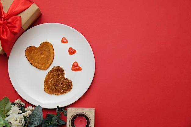 Panqueques en forma de corazón en un plato blanco, composición para el día de San Valentín con comida. Espacio para texto