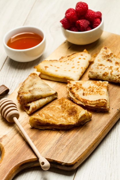 Panqueques con frambuesas y miel en una tabla de cocina de madera