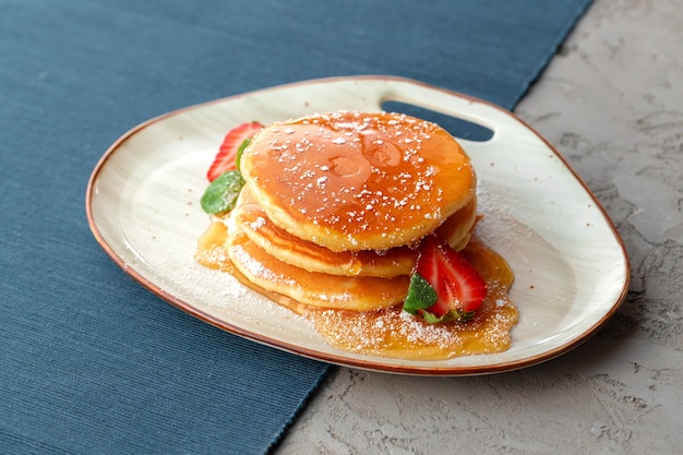 Panqueques con fresa y jarabe de arce en mesa