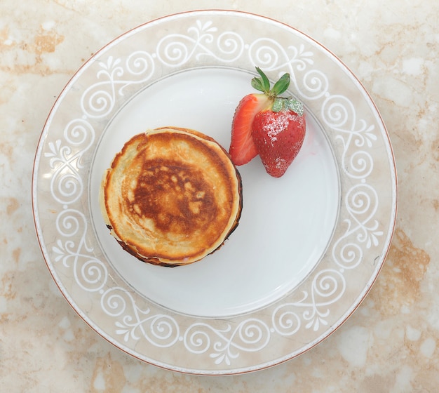 Panqueques con fresas, espolvoreados con vainilla en el plato