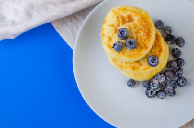 Panqueques con fresas, frambuesas, arándanos en una superficie azul