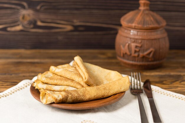 Panqueques fritos con un tarro de miel Comida nacional rusa y ucraniana Enfoque selectivo