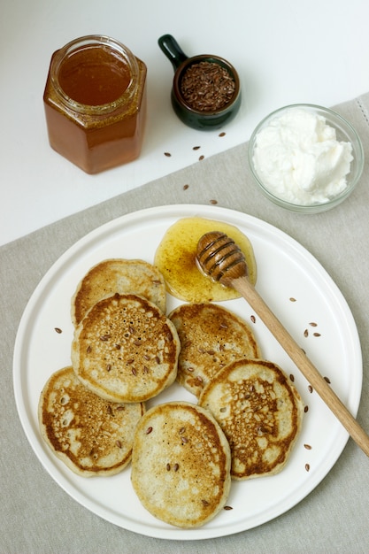 Panqueques de lino servidos con miel y queso crema. Estilo rústico