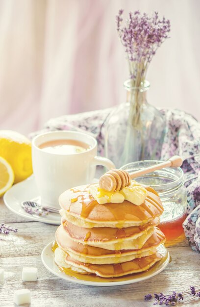 Panqueques con mantequilla y miel y té de limón para el desayuno. enfoque selectivo