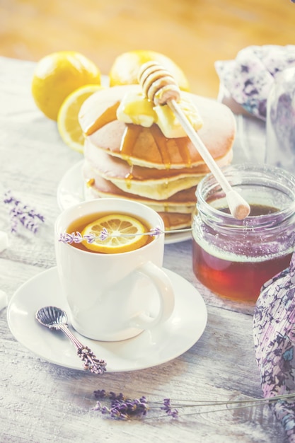 Panqueques con mantequilla y miel y té de limón para el desayuno. enfoque selectivo