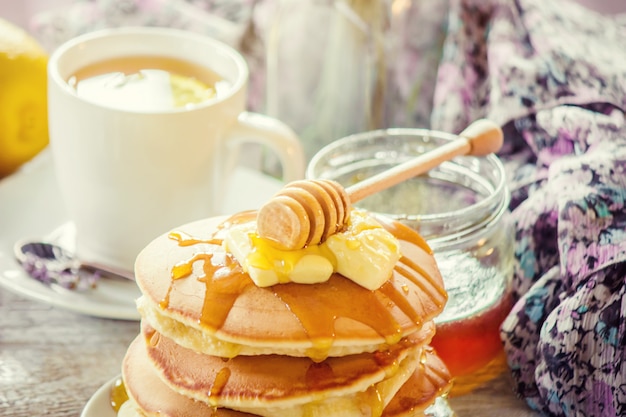 Panqueques con mantequilla y miel y té de limón para el desayuno. enfoque selectivo