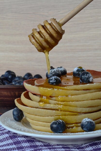 panqueques con miel y bayas para desayunar en una mesa cubierta con una toalla morada