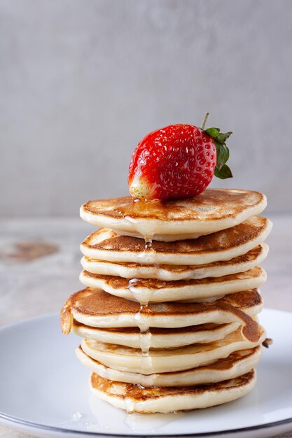 Panqueques con miel y fresas se encuentran en un plato