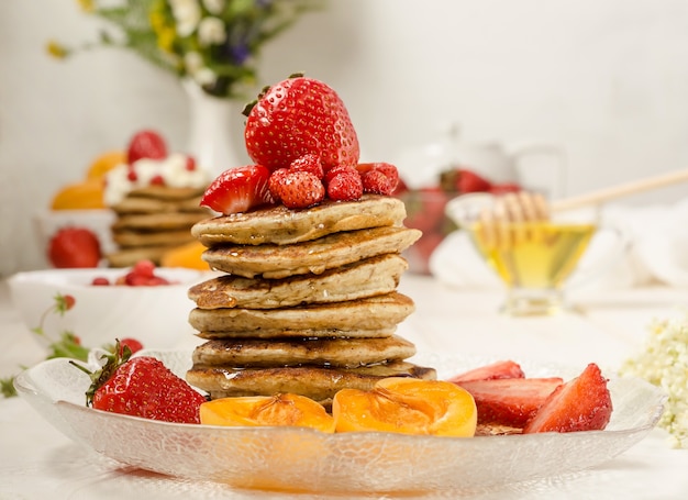 Panqueques con miel, fresas y frutas de cerca