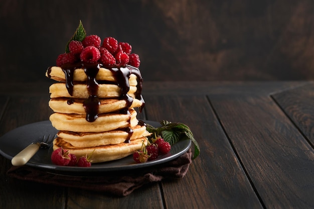 Panqueques Panqueques con frambuesa fresca con glaseado de chocolate o coberturas en un tazón gris sobre fondo de mesa de madera vieja Panqueques americanos clásicos caseros Página para el concepto de revista