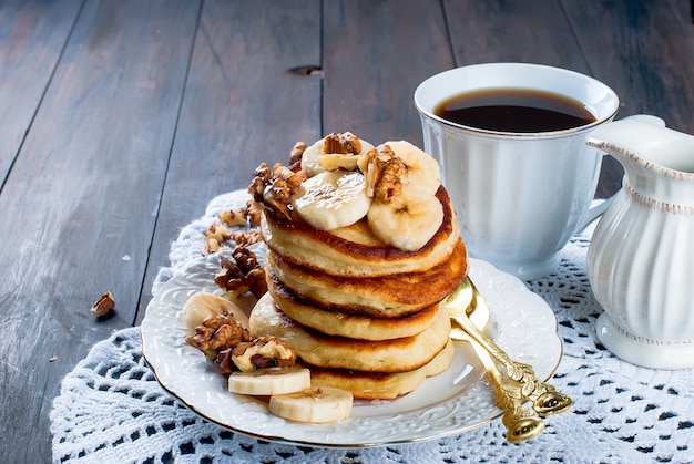 Panqueques con plátano, nueces, miel y taza de café oscuro