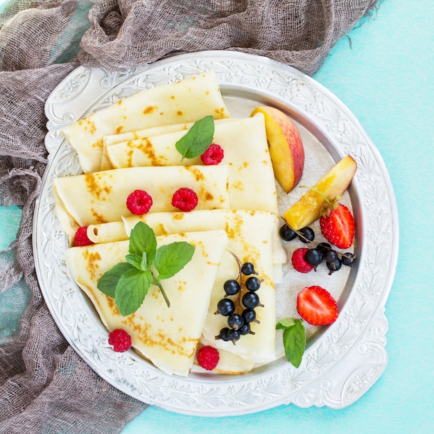 Panqueques en un plato con miel y bayas frescas