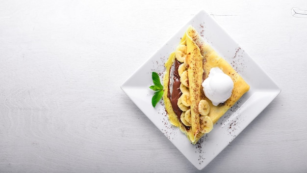 Panqueques con postre de chocolate y plátano Sobre un fondo de madera Vista superior Espacio libre para el texto