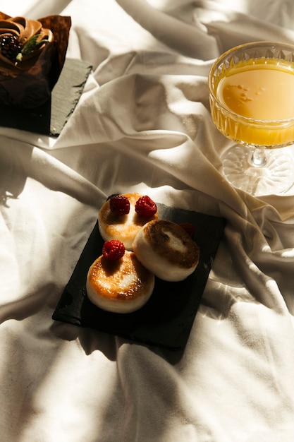 Panqueques de queso con jugo de naranja sobre fondo de tela blanca