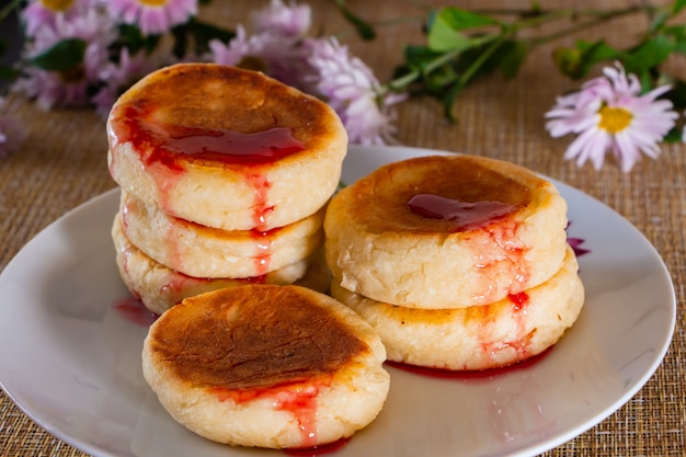 Panqueques de queso con mermelada en un plato sobre un fondo marrón. Comida de desayuno