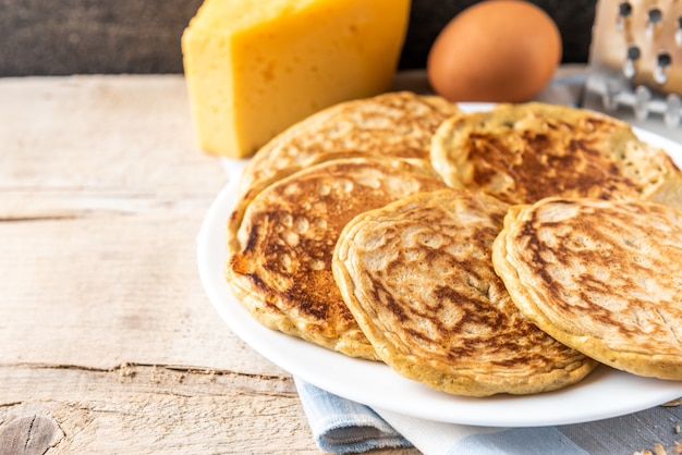 Panqueques con queso en mesa de madera oscura.