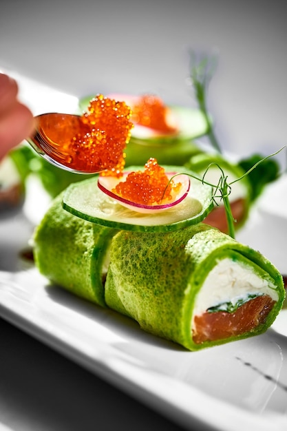 Panqueques rellenos de queso crema y salmón en plato Fondo de mantel blanco Blini ucraniano