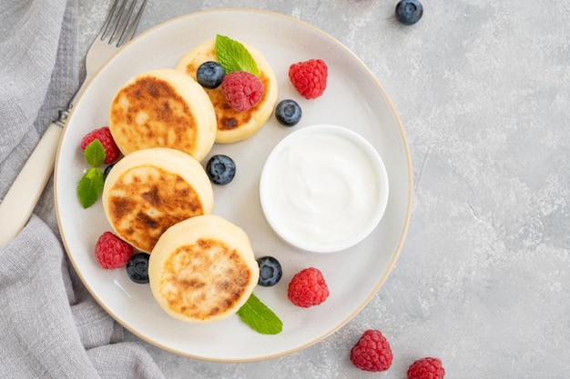 Panqueques de requesón con crema agria de bayas frescas y miel Syrniki ucraniano y ruso