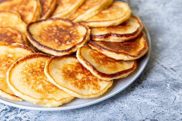 Panqueques de requesón (syrniki). Tartas de queso casero de requesón en un plato grande. Plato tradicional ruso. De cerca.