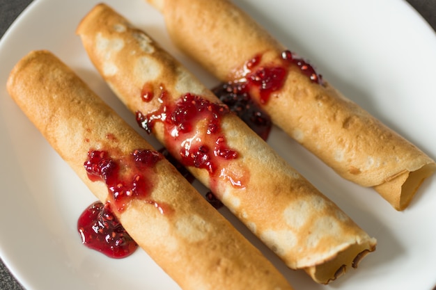 Panqueques rusos tradicionales con mermelada de frambuesa en la parte superior.