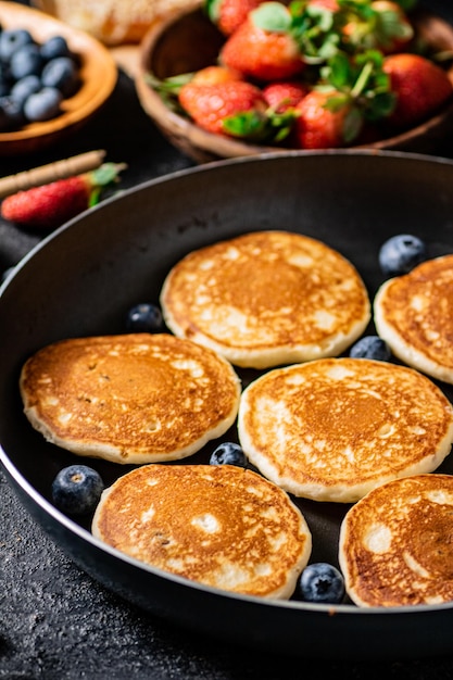 Foto panqueques en una sartén con bayas frescas