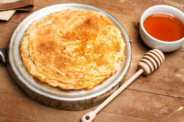 Panqueques y un tazón de miel en una mesa de madera