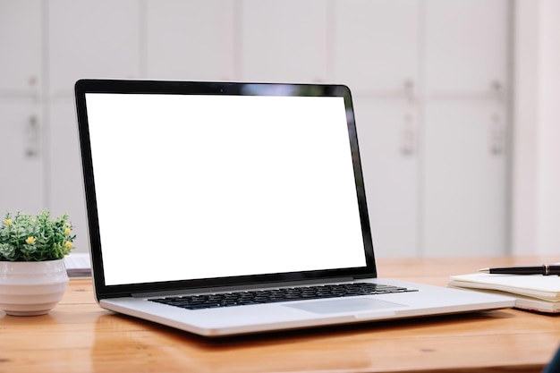 Pantalla blanca en blanco de la computadora portátil en la mesa de madera en la plantilla de maqueta de la cafetería para su texto