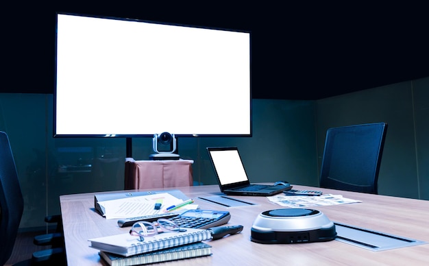 Pantalla blanca en pantalla de televisión y computadora portátil con equipo de reunión en la mesa en la sala de reuniones