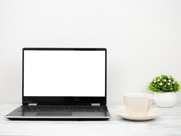 Pantalla blanca portátil con taza de café y jarrón mínimo en concepto de espacio de trabajo de mesa de madera