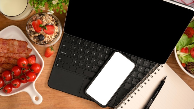 Una pantalla blanca de teléfono inteligente en una tableta con un desayuno saludable en la mesa