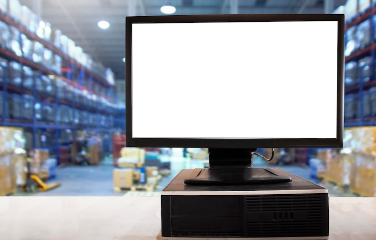 Foto pantalla en blanco de la computadora en la mesa en el almacén de distribución suministros de almacén de envío de la cadena de suministro