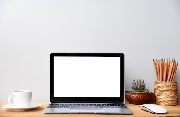 Foto pantalla en blanco computadora portátil moderna con mouse teléfono inteligente y suculenta en mesa de madera en fondos de vista de oficina