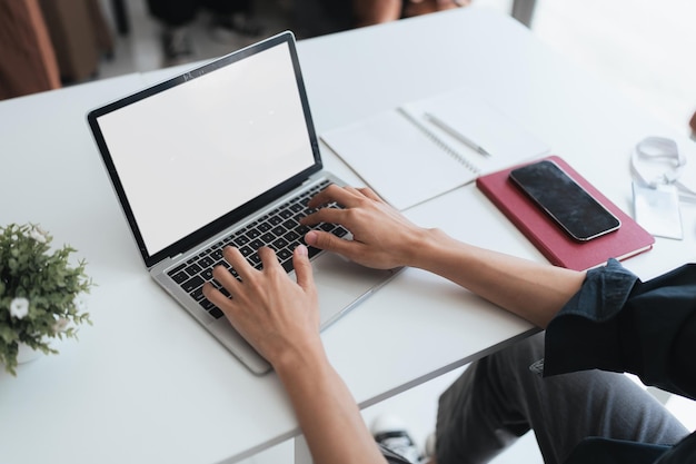 pantalla en blanco de la mano del hombre trabajando en una computadora portátil y trabajando mientras está sentado en la mesa maqueta pantalla en blanco para exhibición de productos o diseño gráfico