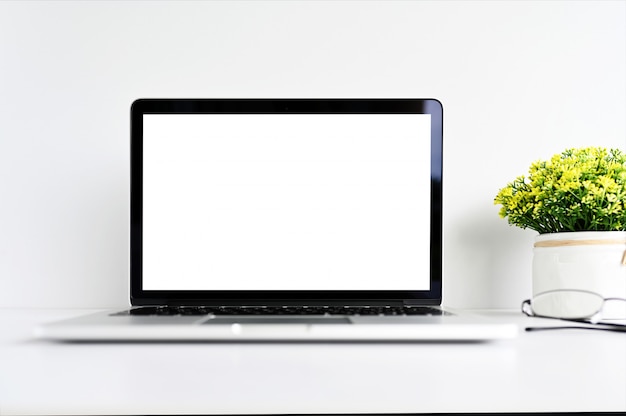 Foto pantalla en blanco moderno ordenador portátil con ratón, teléfono inteligente y suculentas sobre mesa de madera en el fondo de la oficina