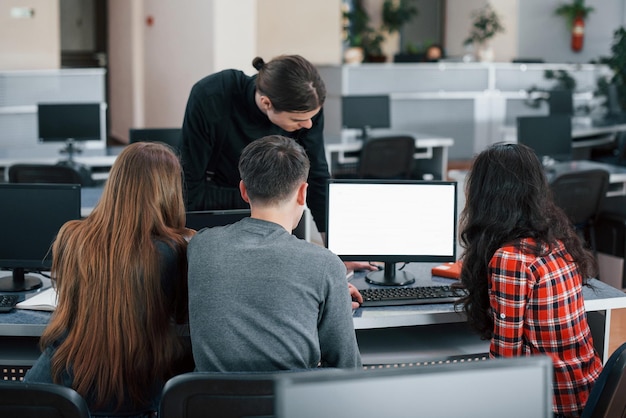 Foto pantalla de color blanco ponga su texto allí grupo de jóvenes con ropa casual trabajando en la oficina moderna