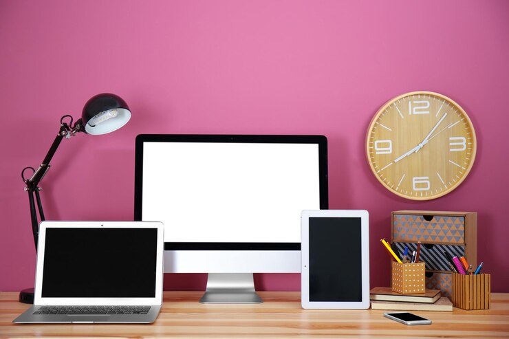 Foto pantalla de computadora, tableta portátil y teléfono inteligente en la mesa de madera contra la pared de color