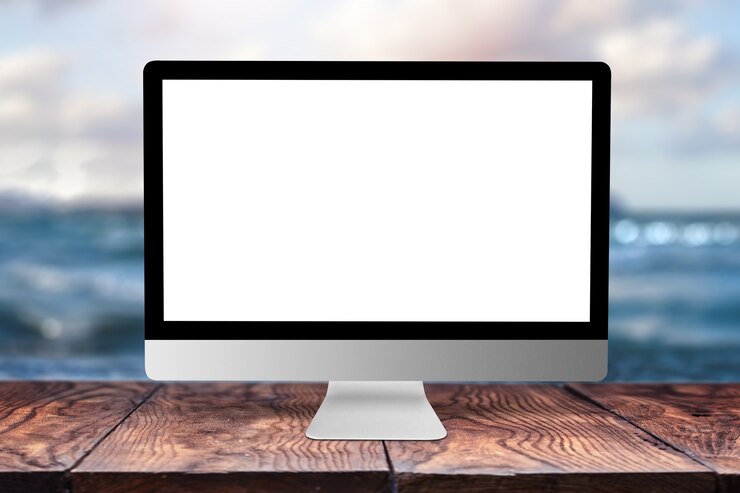 Foto pantalla de ordenador en blanco blanco sobre una mesa de madera contra el paisaje marino borrosa natural con bokeh, copie el espacio. concepto de trabajo de forma remota.