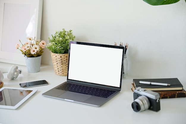 Pantalla de ordenador portátil en blanco en la mesa de escritorio de trabajo blanco