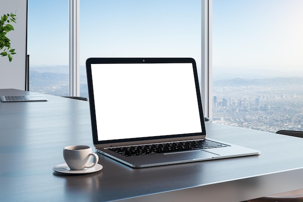 Pantalla de portátil blanca en blanco con espacio de copia para su texto en una mesa de madera oscura con una taza de café en una habitación soleada y vistas al horizonte de la ciudad desde una maqueta de representación 3D de una pared de cristal