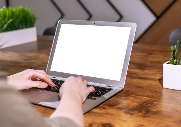 La pantalla del portátil se burla de las manos escribiendo en el teclado de la PC con una pantalla vacía en blanco para la presentación del sitio web Escritorio de oficina