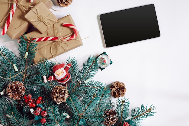 Pantalla de tableta de fondo de compras en línea de Navidad con copia espacio regalos de ramas de abeto sobre fondo blanco ...