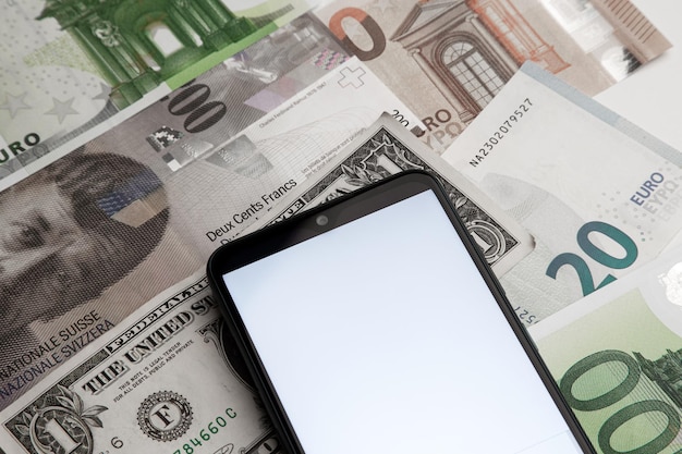 Una pantalla de teléfono inteligente en blanco en el fondo de varios billetes