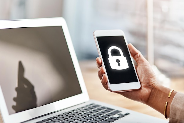 Pantalla de teléfono inteligente de mano y icono de bloqueo en la oficina con pantalla de portátil y ux para software de ciberseguridad Teléfono y computadora personales con protección de símbolos y seguridad contra virus, phishing y hacking