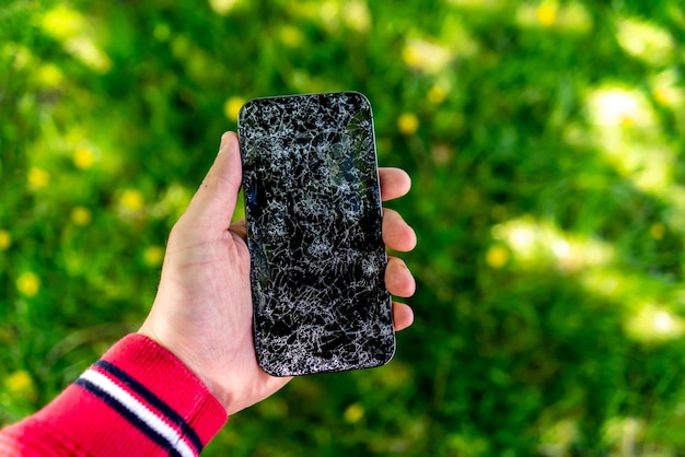 Una pantalla de teléfono rota en la mano de un hombre