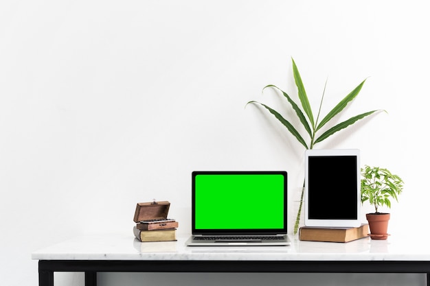 Pantalla verde de la pantalla negra de la computadora portátil y tableta en el escritorio de mármol