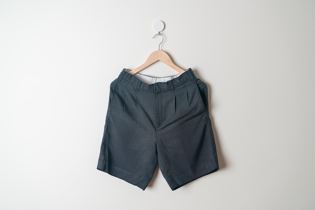 pantalones cortos colgados con un colgador de madera en la pared