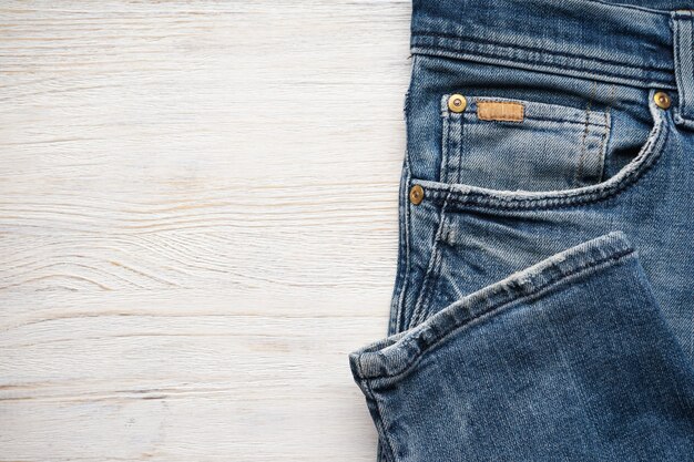 Pantalones de mezclilla doblados sobre una mesa de madera, lugar para el texto. Endecha plana.